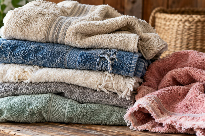 Stapel alter, teilweise ausgefranster Handtücher in verschiedenen Farben, die sich zum Upcycling und Wiederverwenden eignen.